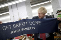 Britain's Prime Minister Boris Johnson hold a scarf with slogan "Get Brexit Done" as he visits John Smedley Mill in Matlock, England, Thursday, Dec. 5, 2019. Britain is holding a general election a week from now and fractures are emerging within jittery political parties unsure how a volatile electorate will judge them. Conservative Prime Minister Boris Johnson and main opposition Labour Party leader Jeremy Corbyn both faced criticism of their moral character. (Hannah McKay/Pool Photo via AP)