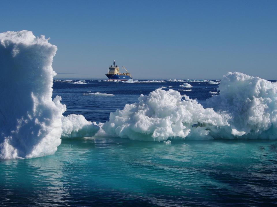 An undersea cable laying vessel sails past icebergs.