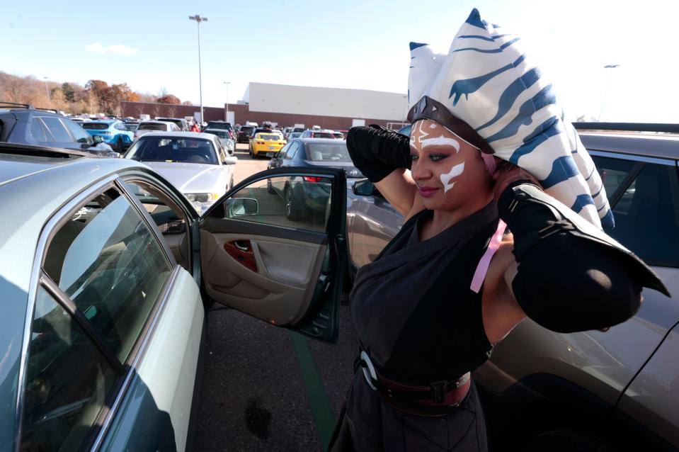 Teresa Robinson, 27 of Pontiac, uses the window of another car to get her outfit on of the Star Wars character Ahsoka before heading into the Motor City Comic Con at the Suburban Collection Showplace in Novi on Saturday, November 11, 2023. 
Robinson guesses she spent about $350 for the outfit including color contact lenses.