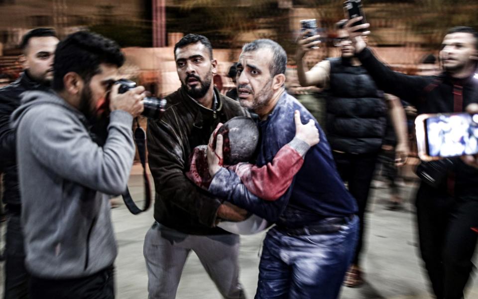A man carrying a child, injured following Israeli bombardment, arrives to Nasser hospital in Khan Yunis