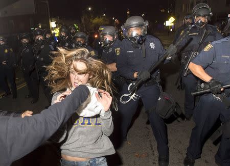 A protester flees as police officers try to disperse a crowd comprised largely of student demonstrators during a protest against police violence in the U.S., in Berkeley, California early December 7, 2014. REUTERS/Noah Berger