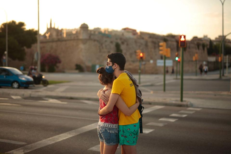 A young couple embraces as the sun sets in the Balearic Islands (AP)