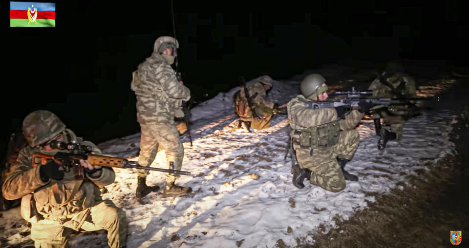 This photo taken from a video released by Azerbaijan's Defense Ministry on Wednesday, Nov. 25, 2020, shows Azerbaijan's army soldiers and a deminer looking on during a mine clearance in Kalbajar region of Azerbaijan. The Kalbajar district bordering Armenia, which houses one of the two roads linking Nagorno-Karabakh and the neighbouring country and has strategic significance for Armenians and Azeris, is due to be handed over to Azerbaijan according to a Russia-brokered cease-fire agreement between two countries in the long-running conflict over the separatist territory. (Azerbaijan's Defense Ministry via AP)