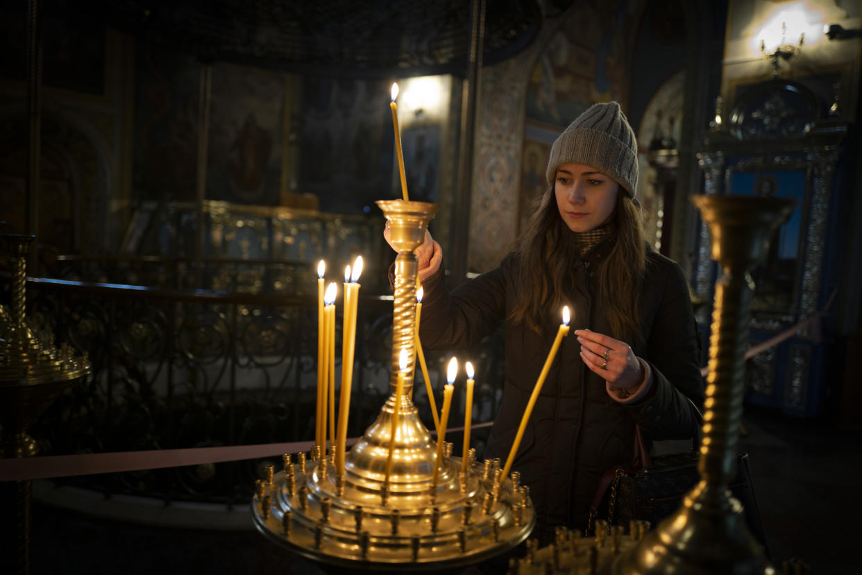 A girl lights a candle before the start of the Orthodox Christmas in the St. Michael's Monastery of Kyiv, Ukraine, Friday, Jan. 6, 2023. Russian President Vladimir Putin on Thursday ordered Moscow's armed forces to observe a 36-hour cease-fire in Ukraine this weekend for the Russian Orthodox Christmas holiday, but Ukrainian President Volodymyr Zelenskyy questioned the Kremlin's intentions. (AP Photo/Bela Szandelszky)