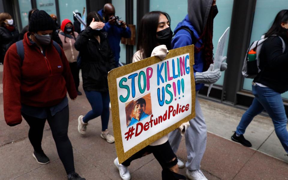 A protester holding a sign reading "Stop Killing Us" navigates along Chicago's Loop during a peaceful protest on Wednesday - AP