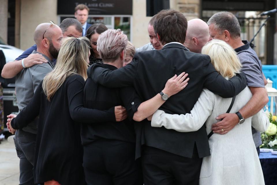 Family members of the three victims comfort each other after lighting candles during a vigil at Market Place, Reading, in memory of David Wails, Joseph Ritchie-Bennett and James Furlong, following the attack (PA Archive)