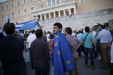 A protester wrapped in a European Union flag attends a rally calling on the government to clinch a deal with its international creditors and secure Greece's future in the Eurozone, in Athens, Greece, June 22, 2015. REUTERS/Alkis Konstantinidis