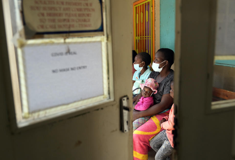 Women holding babies take their places on wooden benches at a clinic in Harare, Zimbabwe, Thursday, Sept. 15, 2022. Church members in Zimbabwe are getting their children vaccinated against measles in secret amid a deadly outbreak. It's to avoid being shunned by religious leaders who are opposed to modern medicine. (AP Photo/Tsvangirayi Mukwazhi)