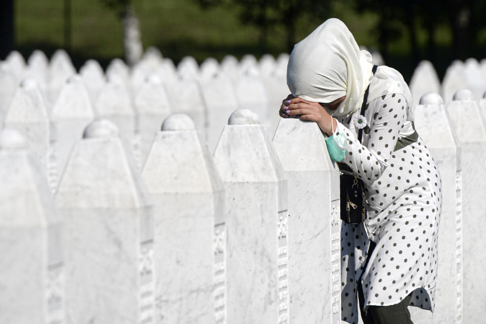 A woman leans on a grave stone in Potocari, near Srebrenica, Bosnia, Saturday, July 11, 2020. Nine newly found and identified men and boys were laid to rest as Bosnians commemorate 25 years since more than 8,000 Bosnian Muslims perished in 10 days of slaughter, after Srebrenica was overrun by Bosnian Serb forces during the closing months of the country's 1992-95 fratricidal war, in Europe's worst post-WWII massacre. (AP Photo/Kemal Softic)