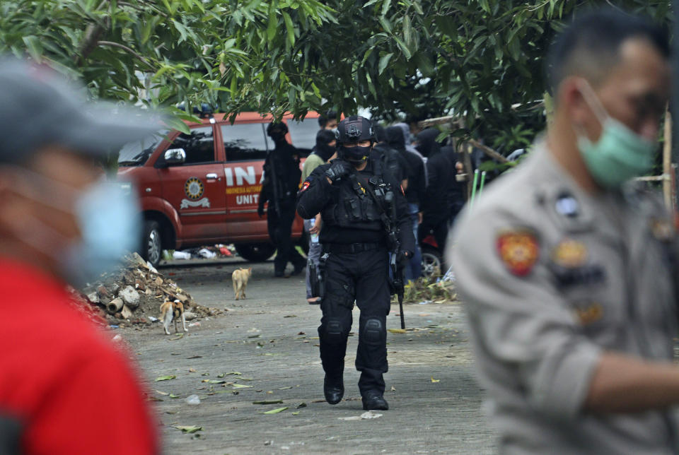 Police officers walk outside the site where two suspected militants were killed during a raid in Makassar, South Sulawesi, Indonesia, Wednesday, Jan. 6, 2021. Members of Indonesia's anti-terrorism police squad killed the two suspected militants who they believe were connected to a deadly suicide attack at a Roman Catholic cathedral in the southern Philippines, officials said. (AP Photo/Masyudi S. Firmansyah)