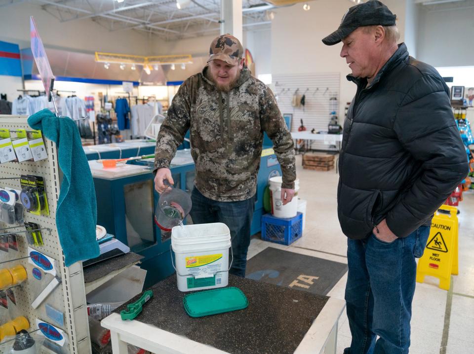 Sportsmen's Direct employee Spencer Szymkowicz, left, helps customer Ronald Buchman purchase a scoop of minnows on Thursday, Feb. 15, 2024. The lack of winter ice on Lake St. Clair has prevented ice fishers from hitting the lake, denting the store's revenues significantly.