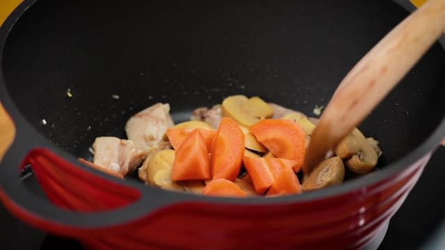 stir frying carrots, mushrooms and chicken in a pot