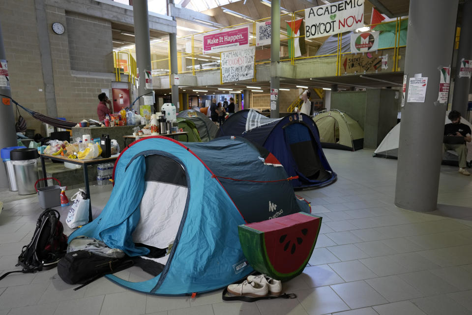 FILE - Signs and a food table are set up in a tent camp, set up by pro-Palestinian students and demonstrators at the University of Antwerp, as students occupy parts of the campus in Antwerp, Belgium, Tuesday, May 14, 2024. Colleges and universities have long been protected places for free expression without pressure or punishment. But protests over Israel's conduct of the war in Gaza in its hunt for Hamas after the Oct. 7 massacre has tested that ideal around the world. (AP Photo/Virginia Mayo, File)