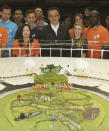 In this photo released Tuesday June 12, 2012 by the Olympic Organising Committee LOCOG, showing Danny Boyle, centre, with volunteers and a model of the rural English scene which will be the centre piece for the London 2012 Olympic Games Opening Ceremony. With 45 days until the Opening Ceremony of the London 2012 Olympic Games artistic director of the ceremony Danny Boyle has unveiled the model and paid tribute to the 10,000 volunteers, cast and crew rehearsing night and day to make the Opening Ceremony a success.(AP Photo / Dave Poultney, Locog)