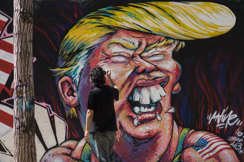 A man takes pictures of a graffiti of Republican presidential candidate Donald Trump in Barcelona on June 7, 2016.