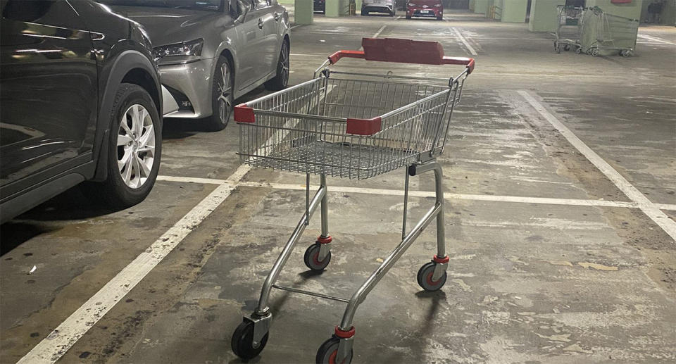 A Coles trolley sits in a parking bay of an underground car park