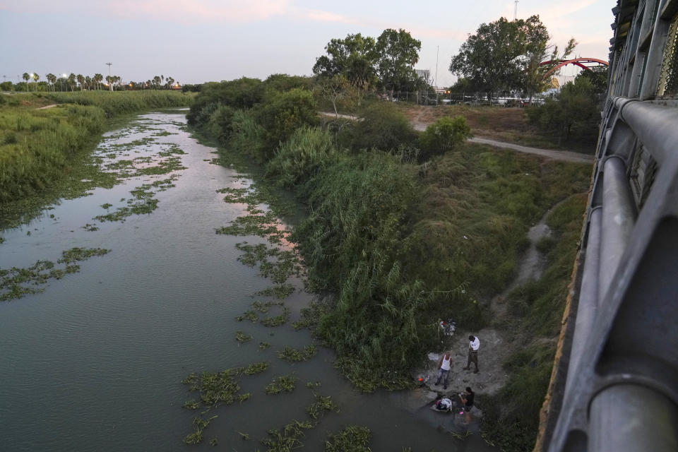 In this Aug. 30, 2019, photo, asylum seekers from Cuba and Nicaragua wash their clothes in the Rio Grande near the Gateway International Bridge in Matamoros, Mexico. They were sent back to Mexico to wait for their asylum case under the "Remain in Mexico" program, officially called the Migrant Protection Protocols. (AP Photo/Veronica G. Cardenas)