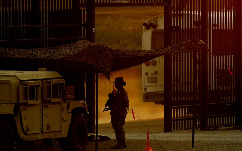 A National Guardsman watches as a bus moves migrants, mostly from Haiti, away from the International Bridge where thousand have formed a makeshift camp, Sunday, Sept. 19, 2021, in Del Rio, Texas. The U.S. flew Haitians camped in the Texas border town back to their homeland Sunday and tried blocking others from crossing the border from Mexico in a massive show of force that signaled the beginning of what could be one of America's swiftest, large-scale expulsions of migrants or refugees in decades. (AP Photo/Eric Gay)