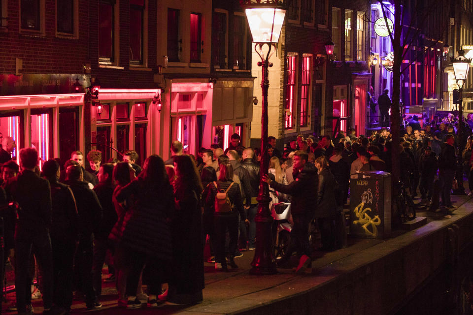 Tourists bathing in a red glow emanating from peep show windows are packed shoulder to shoulder as they shuffle through the alleys in Amsterdam's red light district, Netherlands on March 29, 2019. | Peter Dejong—AP