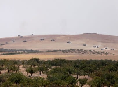 Turkish army tanks and Turkish-backed Syrian fighters make their way in the Syrian border town of Jarablus as it is pictured from the Turkish town of Karkamis, in the southeastern Gaziantep province, Turkey. REUTERS/Stringer