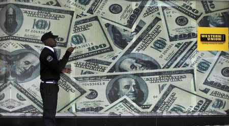 A security guard walks past a montage of old U.S. dollar bills outside a currency exchange bureau ahead in Kenya's capital Nairobi July 23, 2015. REUTERS/Thomas Mukoya