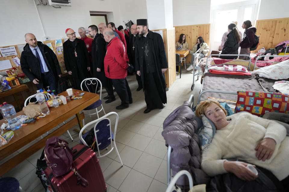 FILE - Under-secretary of the Migrants and Refugees Section of the Holy See's Dicastery Cardinal Michael Czerny, second from left, visits refugees who fled the war from neighboring Ukraine in Barabas, Hungary Wednesday, March 9, 2022. In the past year millions of Ukrainian refugees were welcomed into Europe amid an outpouring of good will, notably from countries like Hungary or Poland that are staunchly opposed to helping take care of migrants from Africa or the Middle East. (AP Photo/Darko Vojinovic, File)