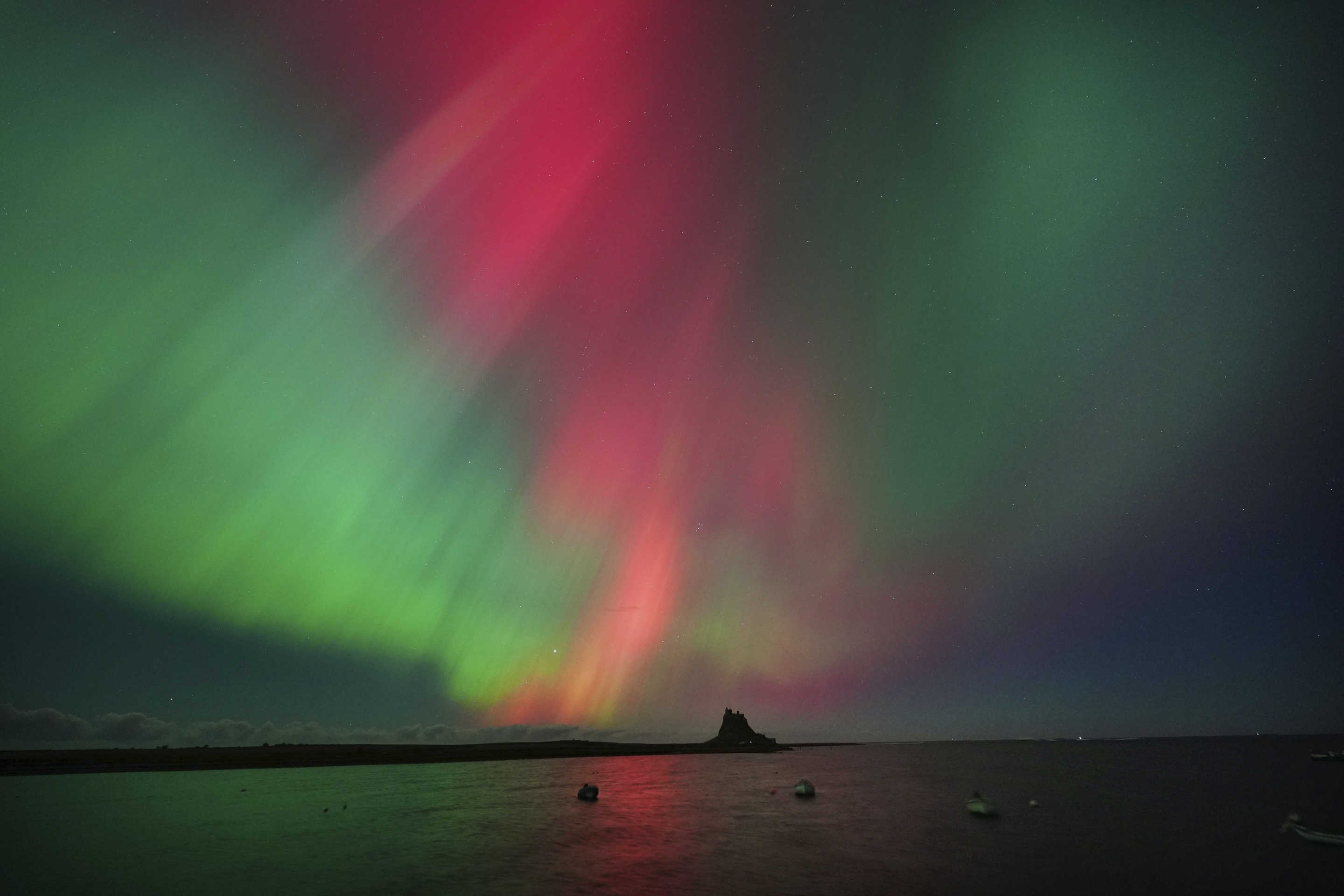 The Northern Lights, also known as the Aurora Borealis, are seen over Holy Island in Northumberland, the North East coast of England, early Friday, Oct. 10, 2024. (Owen Humphreys/PA via AP)