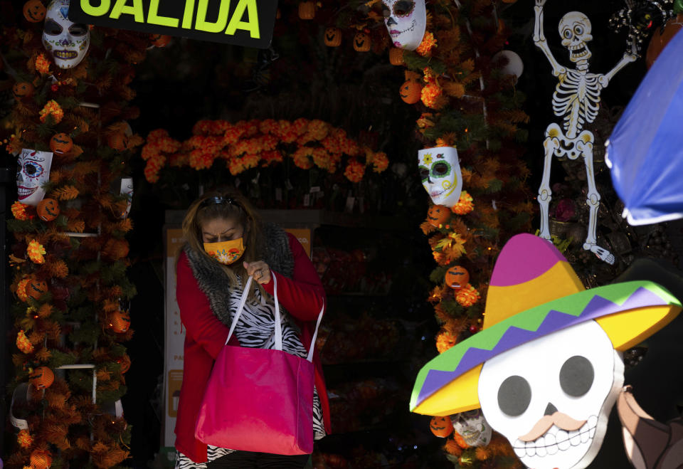 A shopper leaves a Day of the Dead souvenirs store in Mexico City, Friday, Oct. 30, 2020. Prior to the coronavirus pandemic, Mexico’s economy was in recession, and that only deepened with the economic shutdown provoked by measures aimed at slowing the spread of COVID-19 during the second quarter. (AP Photo/Fernando Llano)