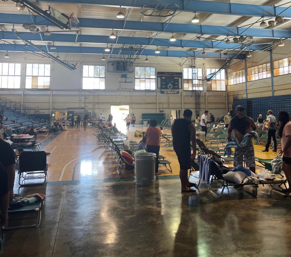 People set up in the War Memorial gymnasium, a shelter that opened in Wailuku, Maui on Aug. 9, 2023. Wildfires in Hawaii fanned by strong winds burned multiple structures in areas including historic Lahaina town, forcing evacuations and closing schools in several communities Wednesday, and rescuers pulled a dozen people escaping smoke and flames from the ocean.