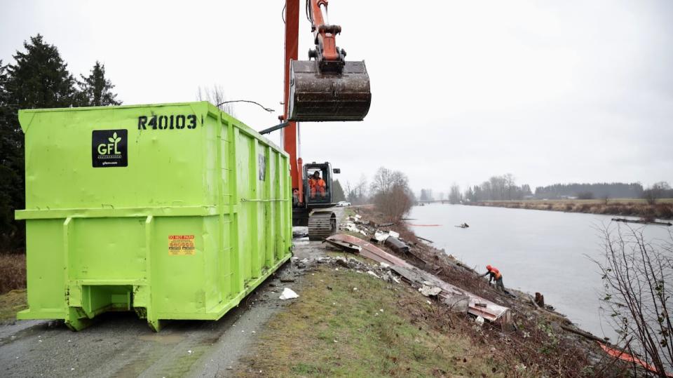 The contracted crew uses a large excavator to haul heavy junk from the Alouette River and into a disposal bin. 