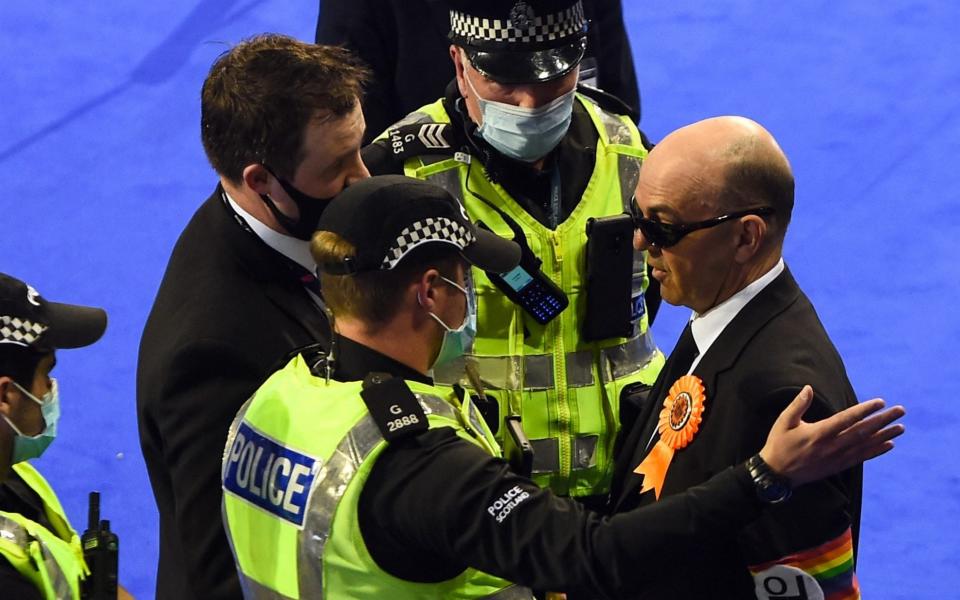 Police eject members of the Liberal Party, including their candidate Derek Jackson during counting the votes of the Scottish elections at the Emirates in Glasgow - ANDY BUCHANAN/AFP