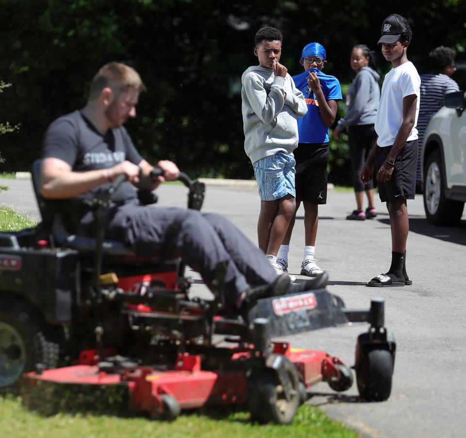 Joshua Thomas, 16, Raiden Felding, 13, and Codey Fortson, 16, watch as Matt Parisi mows the lawn June 17 in Kent. A week earlier, 13 boys rushed to lift Parisi and his mower out of a ditch.