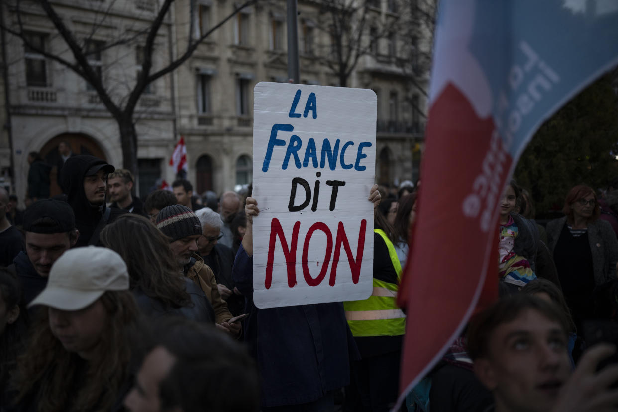 A woman holds a sign reading "France says no" during a demonstration in Marseille, southern France, Thursday, March 16, 2023. French President Emmanuel Macron has shunned parliament and imposed a highly unpopular change to the nation's pension system, raising the retirement age from 62 to 64. (AP Photo/Daniel Cole)