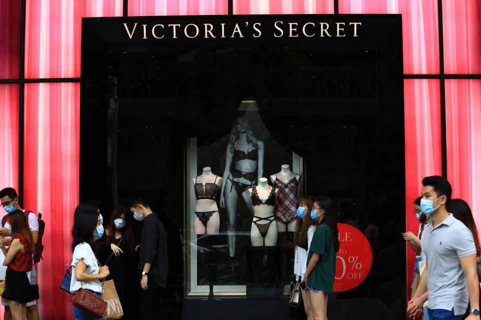 SINGAPORE - JUNE 20:  Shoppers wearing protective masks wait to enter a Victoria's Secret boutique at Orchard Road on June 20, 2020 in Singapore. From June 19, Singapore started to further ease the coronavirus (COVID-19) restrictions by allowing social gatherings up to five people, re-opening of retail outlets and dining in at food and beverage outlets, subjected to safe distancing. Parks, beaches, sports amenities and public facilities in the housing estates will also reopen. However, large scale events, religious congregations, libraries, galleries and theatres will remain closed.  (Photo by Suhaimi Abdullah/Getty Images)