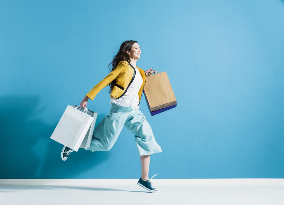 Cheerful happy woman enjoying shopping: she is carrying shopping bags and running to get the latest offers at the shopping center