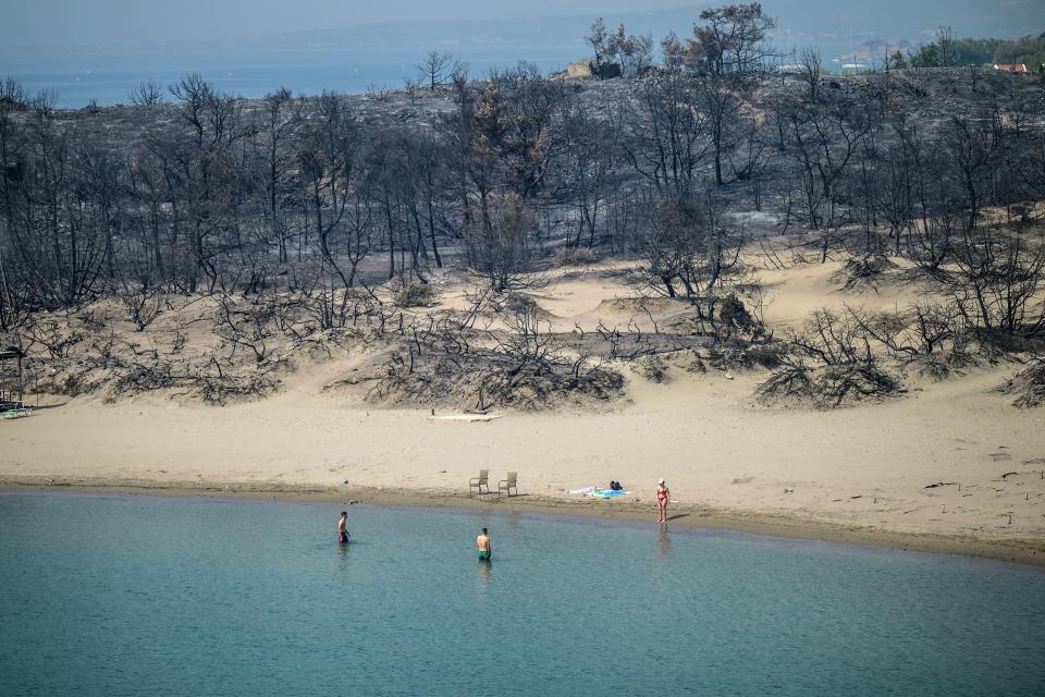 People swim in the sea in southern parts of Rhodes following large-scale wildfires. (Getty Images)