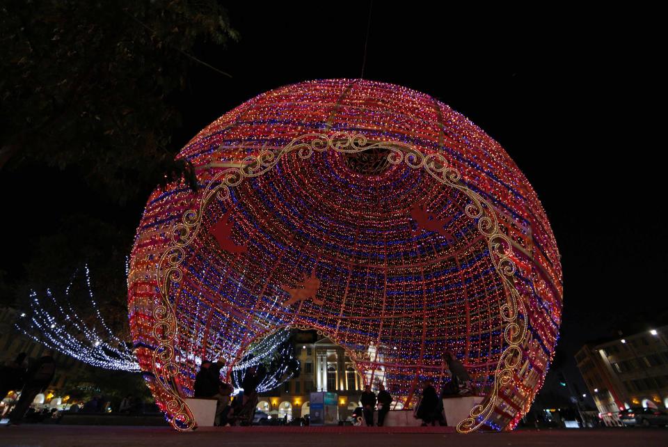 People sit inside a giant Christmas ball as part of Christmas holiday season decorations in Nice