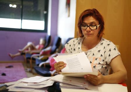 Unemployed hairdresser and mother-of-three Yasmin Rubiano looks at documents at her flat in Madrid June 30, 2014. Picture taken June 30, 2014. REUTERS/Juan Medina