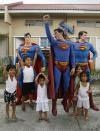 Herbert Chavez poses with his life-sized Superman staues with children outside his house in Calamba Laguna, south of Manila October 12, 2011. In his idolization of the superhero, Chavez, a self-professed "pageant trainer" who owns two costume stores, has undergone a series of cosmetic surgeries for his nose, cheeks, lips and chin down to his thighs and even his skin color to look more like the "Man of Steel". The final result bears little resemblance to his old self. REUTERS/Cheryl Ravelo (PHILIPPINES - Tags: SOCIETY)