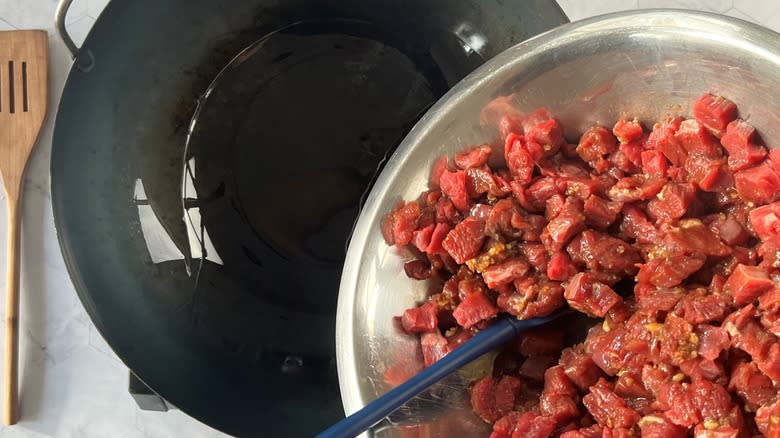 adding diced beef to wok