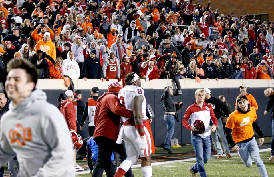 OU's Perrion Winfrey (8) walks of the field as OSU fans rush the field after a 37-33 win over the Sooners on Saturday night at Boone Pickens Stadium in Stillwater.