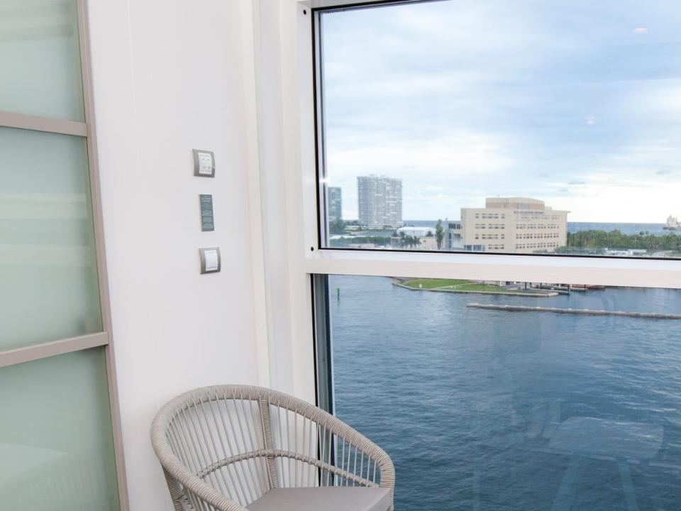 two chairs and a small table in front of a glass wall overlooking the water