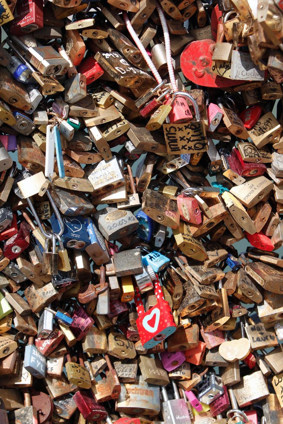 Love locks are fixed on the Pont des Arts Wednesday, April 9, 2014 in Paris. A recent fad among travellers of hitching padlocks on bridges and at tourist attractions worldwide to symbolically immortalize their amorous attraction has swept up this reputed City of Love more than most. Now, two American-born women who live in Paris say they've had enough, launching a petition drive to try to get mostly laissez-faire city officials to step in and do something about what they call an unbearable eyesore in a majestic municipality. (AP Photo/Thibault Camus)