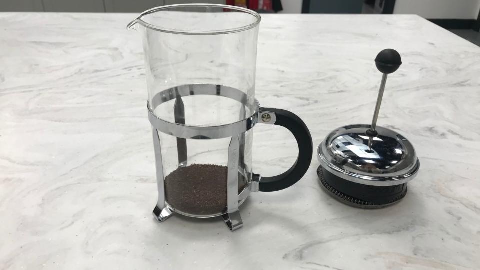 A french press with unsaturated coffee grounds in the bottom