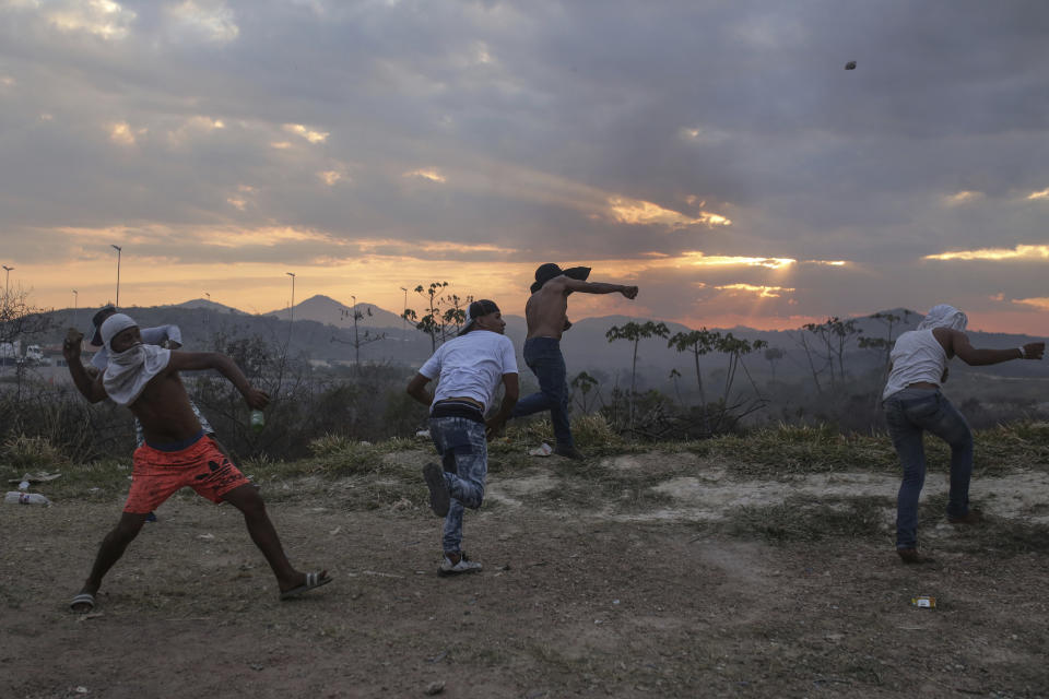 Demonstrators throw stones towards Venezuelan authorities, at the border between Brazil and Venezuela, Saturday, Feb.23, 2019. Tensions are running high in the Brazilian border city of Pacaraima. Thousands remained at the city's international border crossing with Venezuela to demand the entry of food and medicine.(AP Photo/Ivan Valencia)