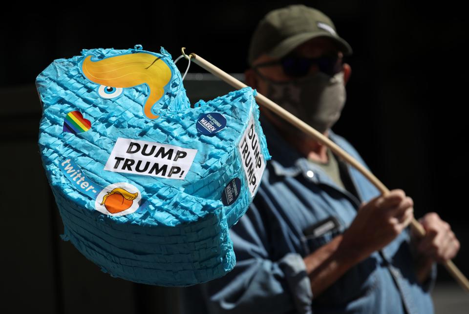 Activist Mike Merrigan holds a piñata shaped like a Twitter logo with Trump hair at a protest May 28, 2020, in San Francisco.