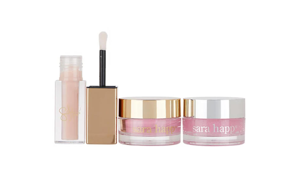 Neutral lip gloss open on the left next to two tubs of Sara Happ lip scrubs