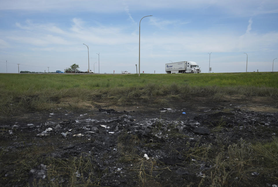 A scorched patch of ground where a bus carrying seniors to a casino ended up after colliding with a semi-trailer truck and burning on Thursday is seen on the edge of the Trans-Canada Highway near Carberry, Manitoba, Friday, June 16, 2023. Police said 15 people were killed and 10 more were sent to hospital. (Darryl Dyck/The Canadian Press via AP)