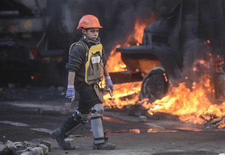 A boy walks by a truck on fire during clashes between anti-government protesters and Interior Ministry members in Kiev February 18, 2014. REUTERS/Andrew Kravchenko/Pool