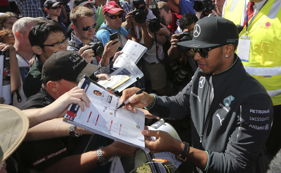 Mercedes driver Lewis Hamilton of Britain signs autographs for fans ahead of the Australian Formula One Grand Prix at Albert Park in Melbourne, Australia, Thursday, March 13, 2014. (AP Photo/Rob Griffith)